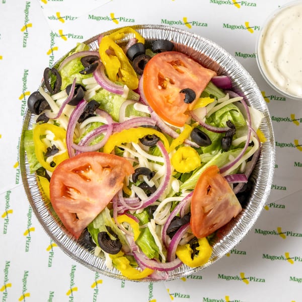 Magoo's California Pizza garden salad with lettuce, tomatoes, olives, onions, and peppers in a foil bowl.