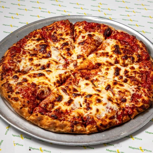A whole Magoo's California Pizza, cut into slices, on a metal tray over a branded tablecloth.