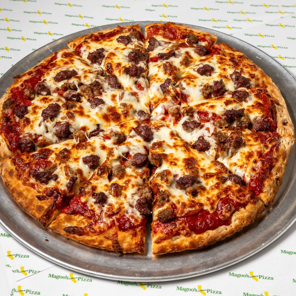A Magoo's California Pizza, sliced into eight pieces, topped with melted cheese and sausage.
