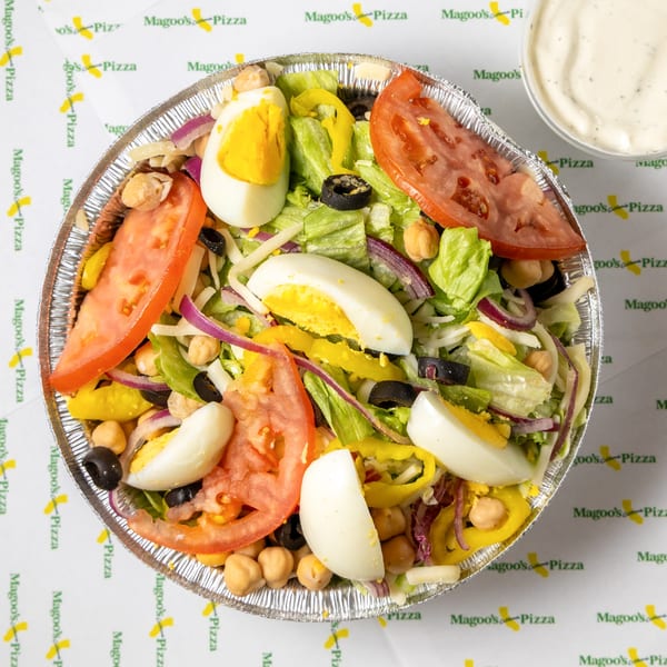 A Magoo's California Pizza salad in a foil bowl with lettuce, tomatoes, eggs, and chickpeas.