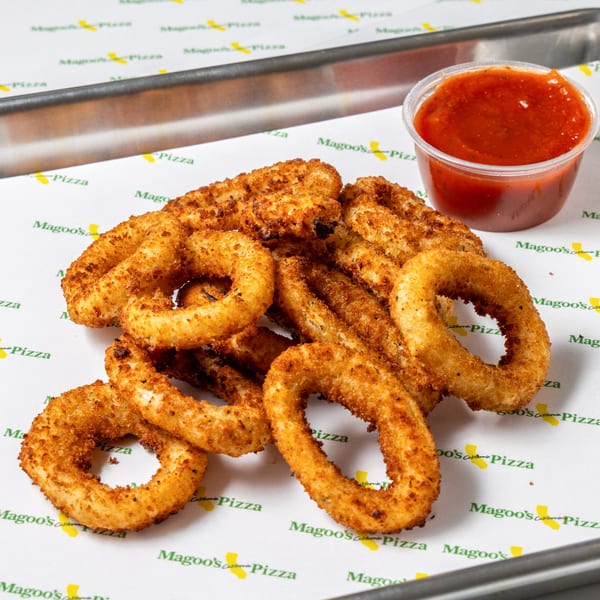 Golden-brown onion rings with a side of red marinara sauce on Magoo's California Pizza branded paper.
