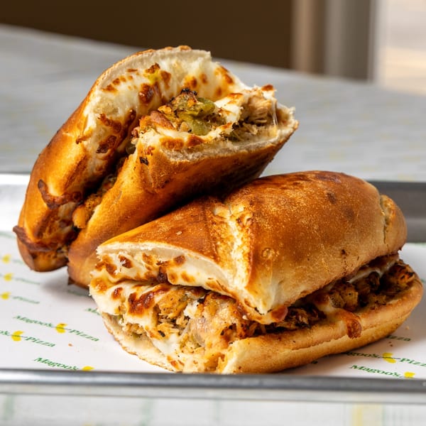 Two Magoo's California Pizza sandwiches, cut in half, filled with melted cheese and meat.
