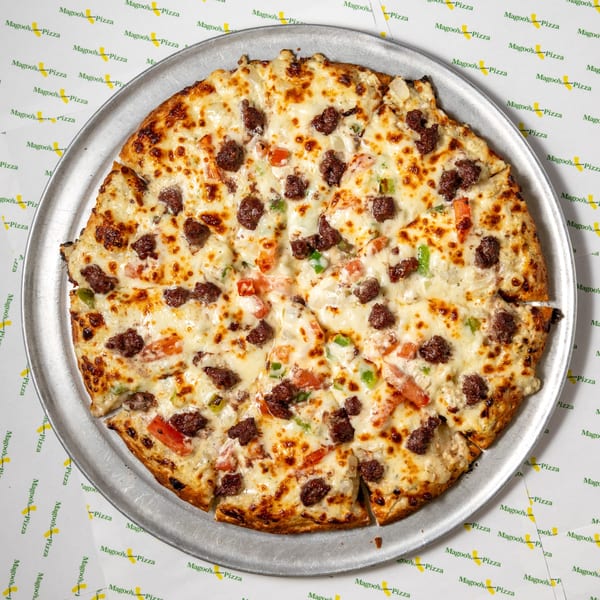 A Magoo's California Pizza with melted cheese, ground beef, tomatoes, and onions on a metal pan.