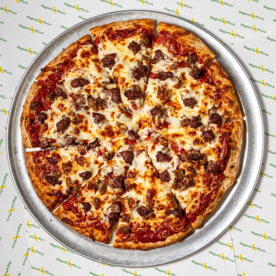 A Magoo's California Pizza with sausage and cheese, sliced on a metal tray.