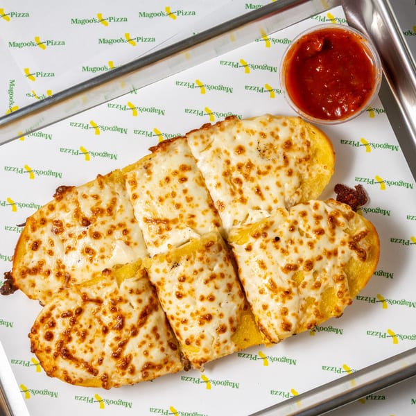 Cheesy garlic breadsticks with a side of marinara sauce on Magoo's California Pizza branded paper.