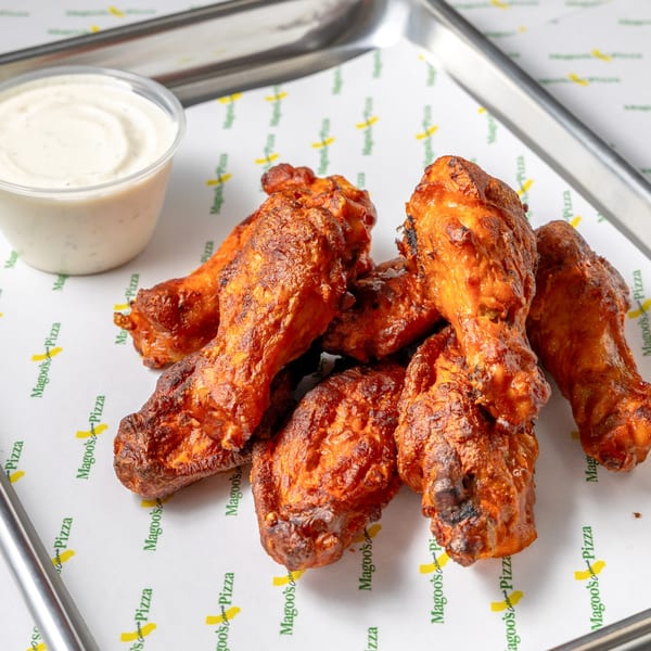 Magoo's California Pizza's spicy chicken wings with ranch dressing on a branded paper-lined tray.