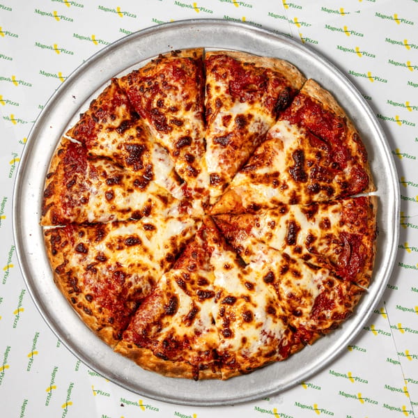 A whole Magoo's California Pizza, cut into slices, on a metal tray over branded paper.