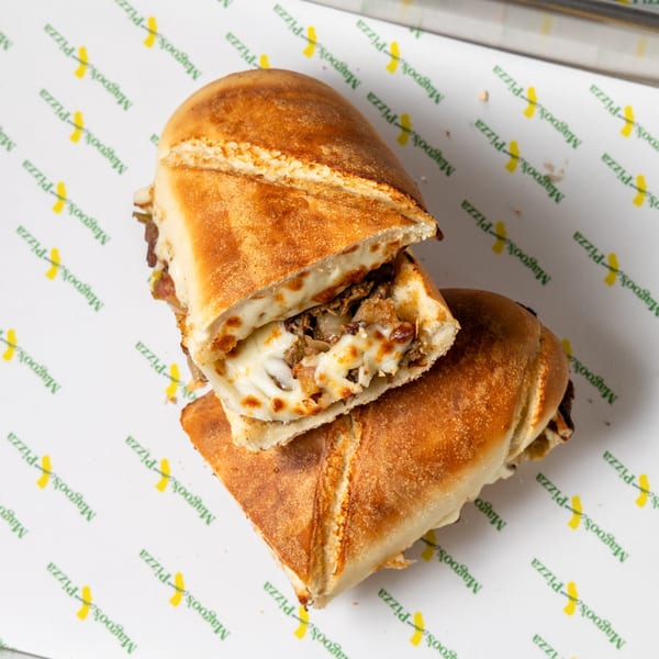 Two halves of a Magoo's California Pizza calzone, filled with melted cheese and meat, on branded paper.
